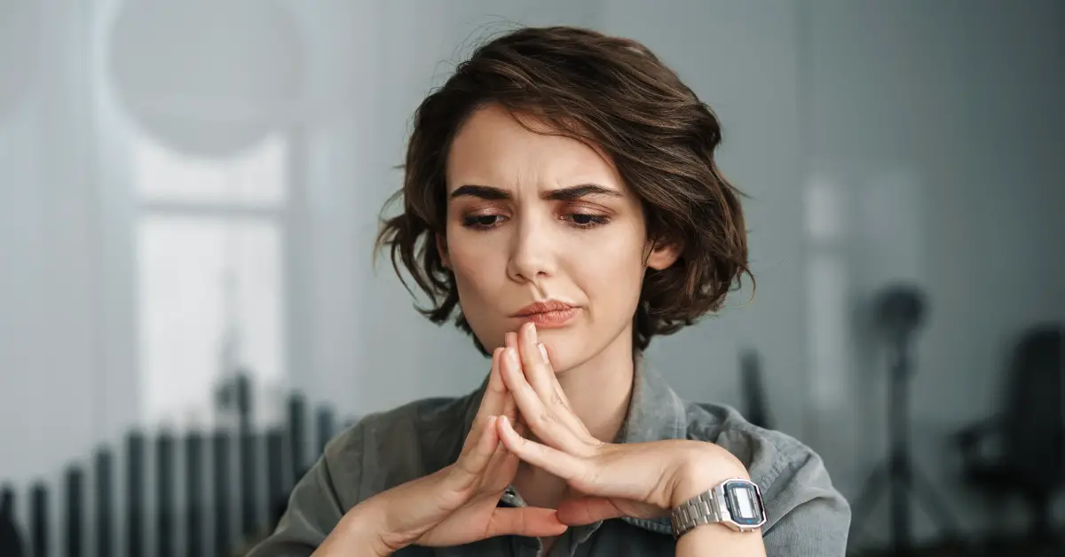 woman thinking with hands pressed together under chin