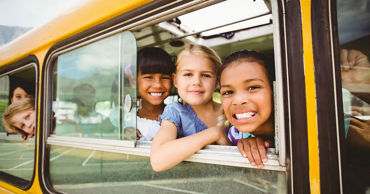 children looking out an open school bus window