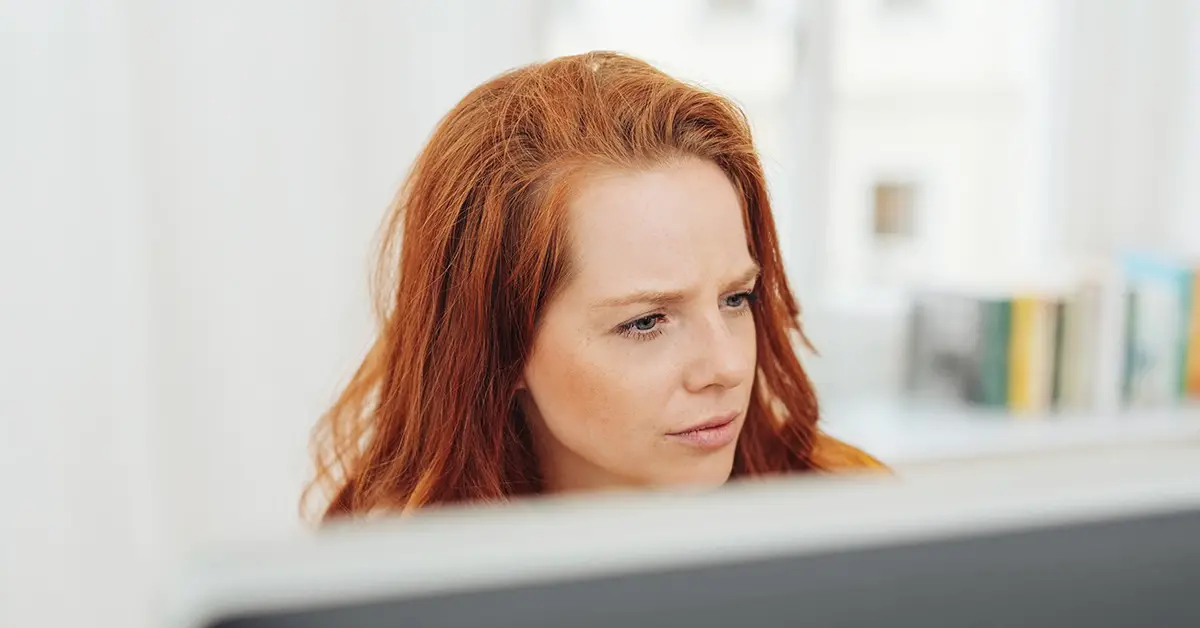 red headed woman who appears to be looking at a computer monitor