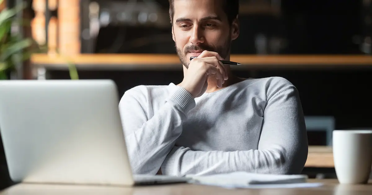 man thinking while looking at open laptop screen