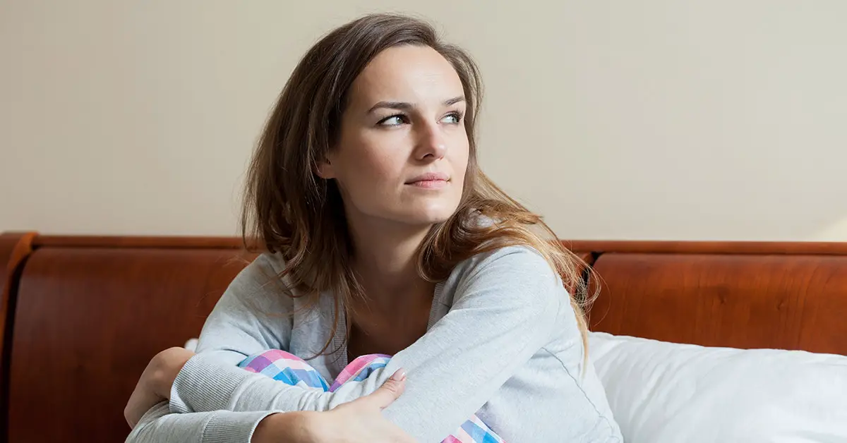 concerned woman sitting on bed