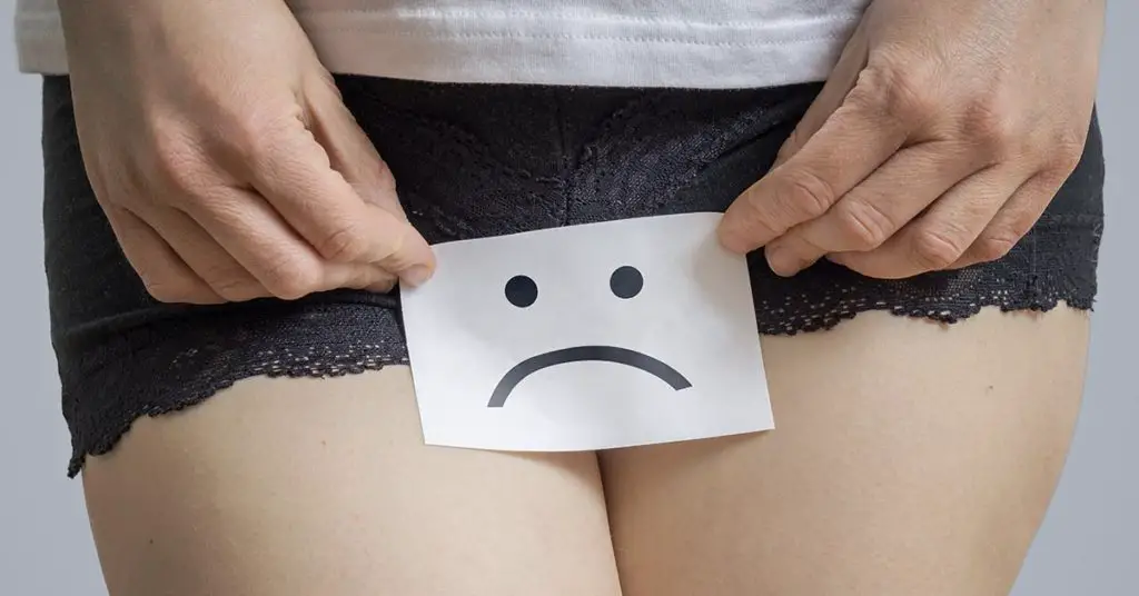 sad face on small piece of paper being placed over female groin area
