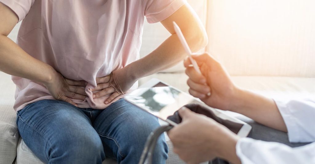 person pressing on lower abdomen during doctors visit 