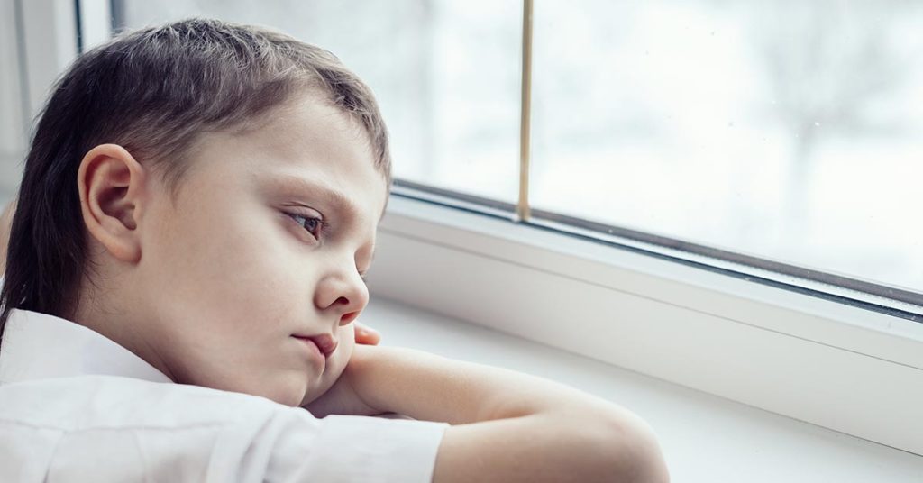 tired boy with head rested on windowsill 