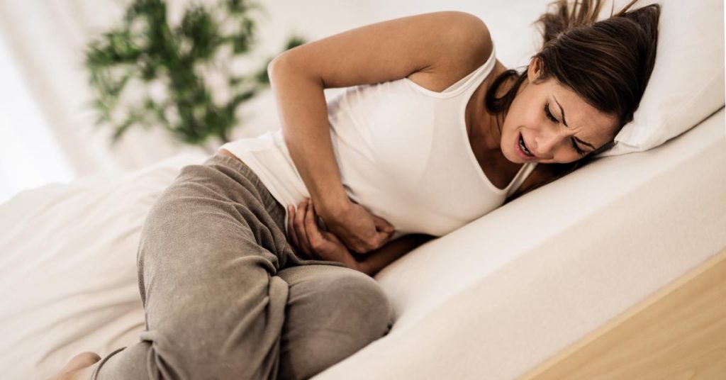 woman on bed with sever abdominal pain