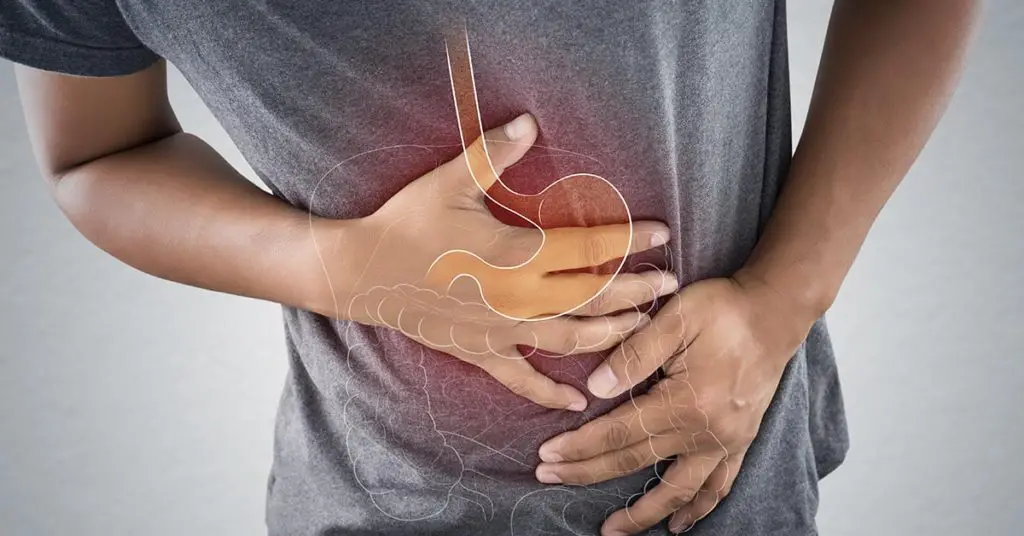 man holding abdomen with illustration of digestive system overlayed