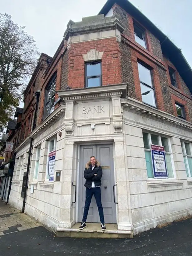 Adam Deering standing outside the very bank that denied him his first loan. 