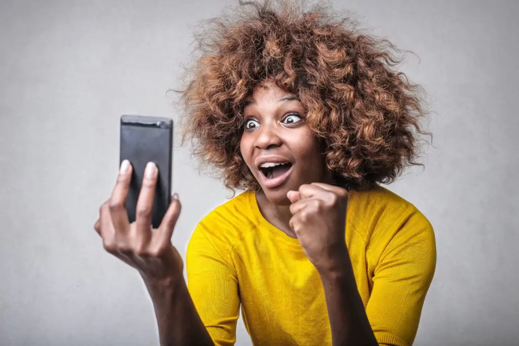 woman with wild hair looking at cellphone surprised