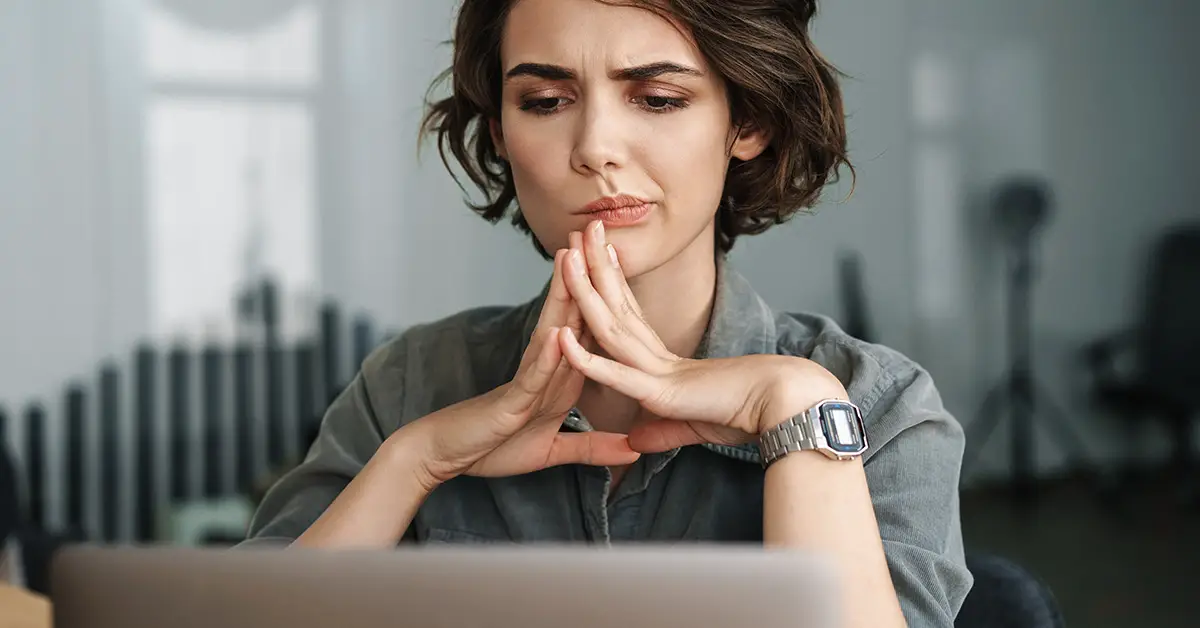 woman pondering with fingers pressed together just under chin
