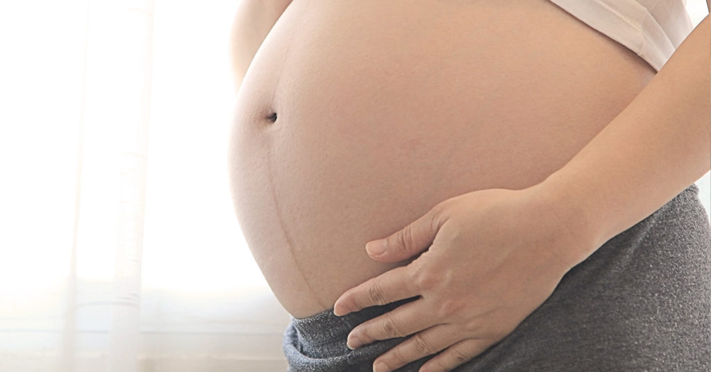 Pregnant Woman Lifts Shirt To Show Protruding Belly And Shares Truth About Rare Pregnancy - Featured image