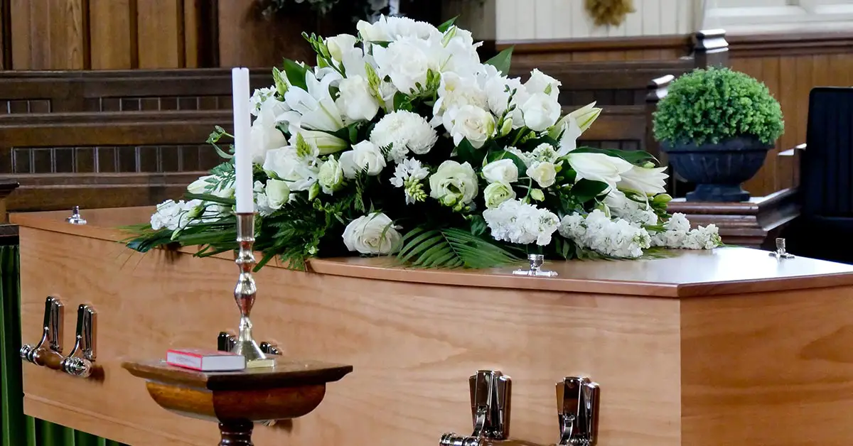 casket with white flowers placed on it at a funeral