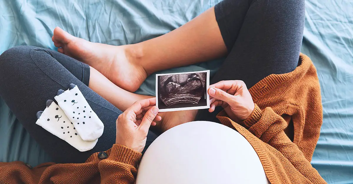 pregnant woman looking at ultrasound photo of twins