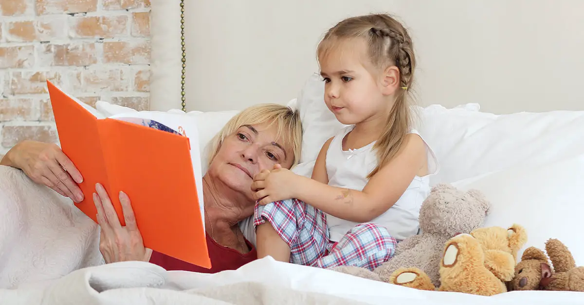 grandparent with grandchild reading a story in bed