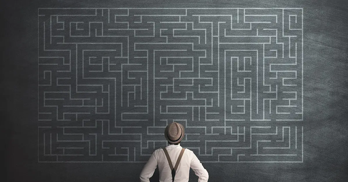 man with a large maze detailed on the wall in front of him
