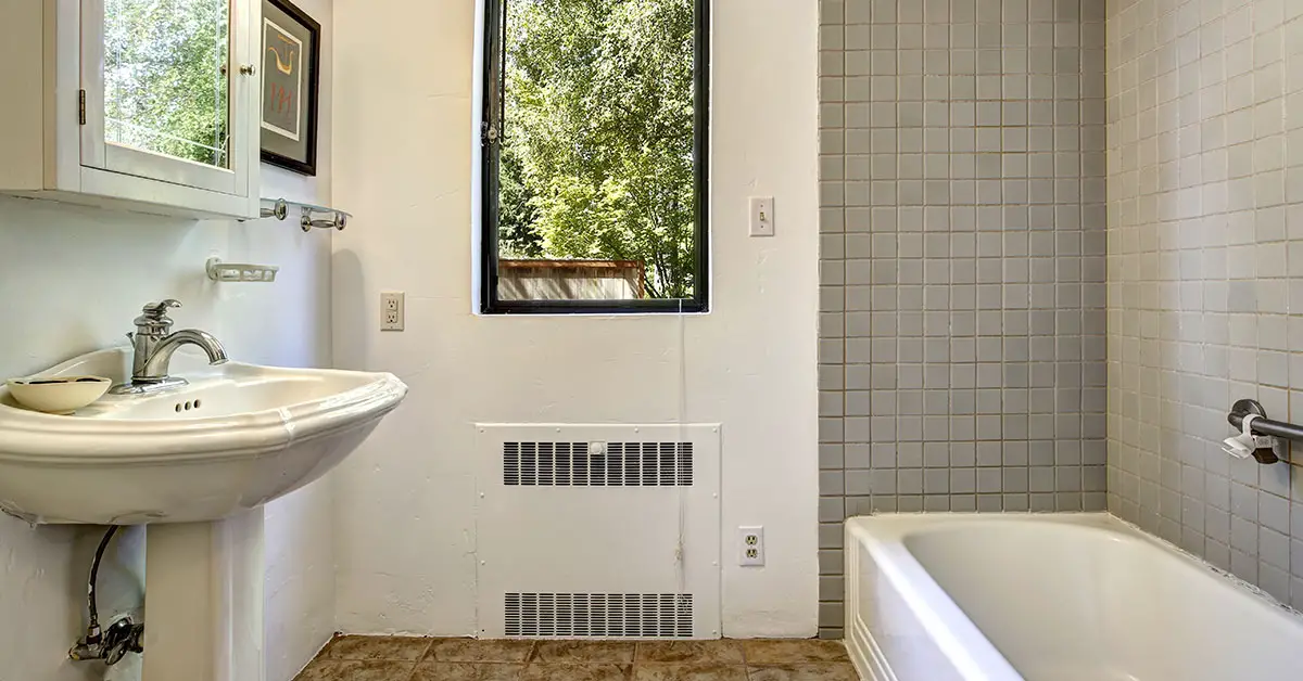 a bathroom. a sink and bathtub with a window revealing greenery outside