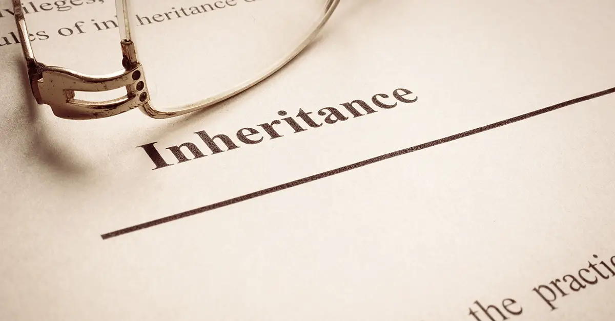 document with text "Inheritance." Reading glasses have been placed just above the text