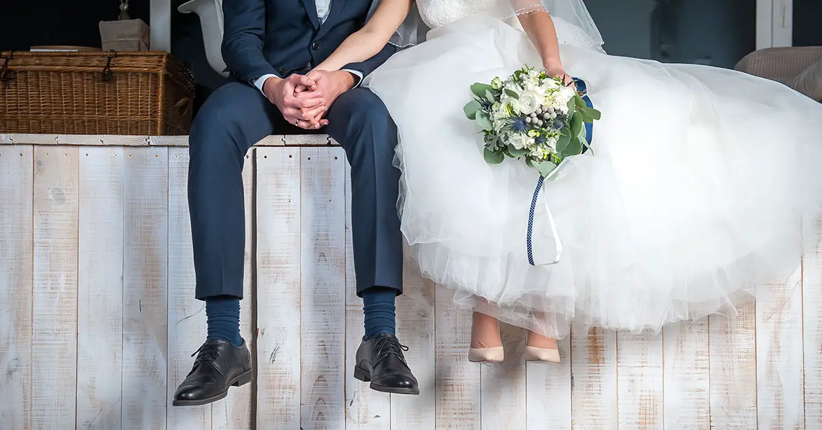 bride and groom sitting on the ledge of a wooden stage