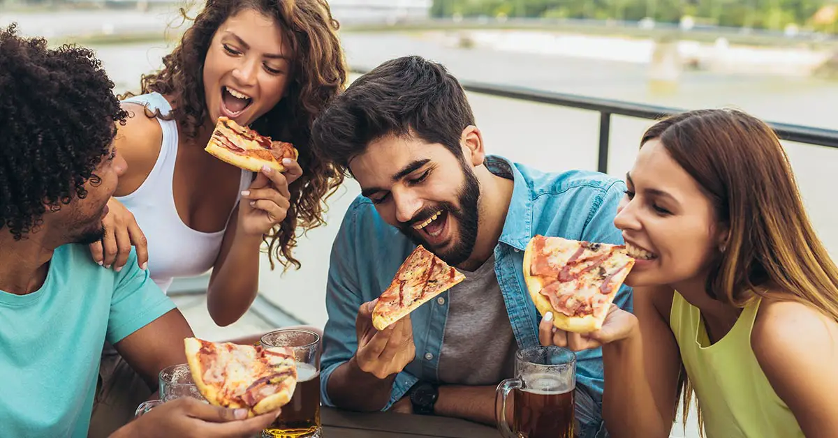 group of 4 people eating pizza outside