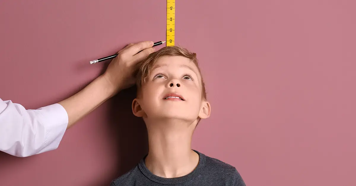 boy being measured against a pink wall