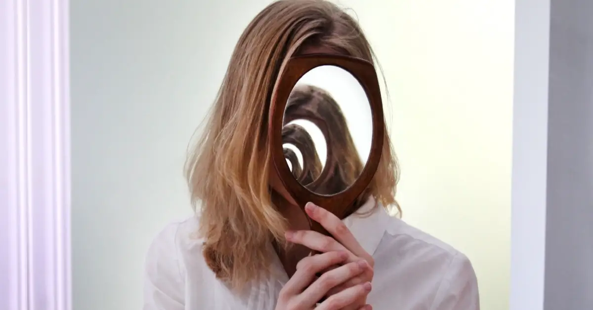 illusion showing multiple reflections of a woman holding a mirror over her face