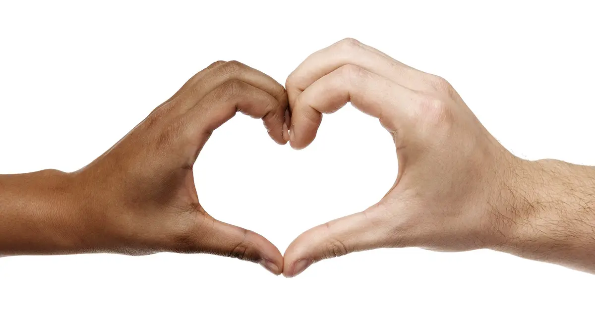 two hands coming together to form a heart. One hand is of darker complexion and the other is of lighter complexion.