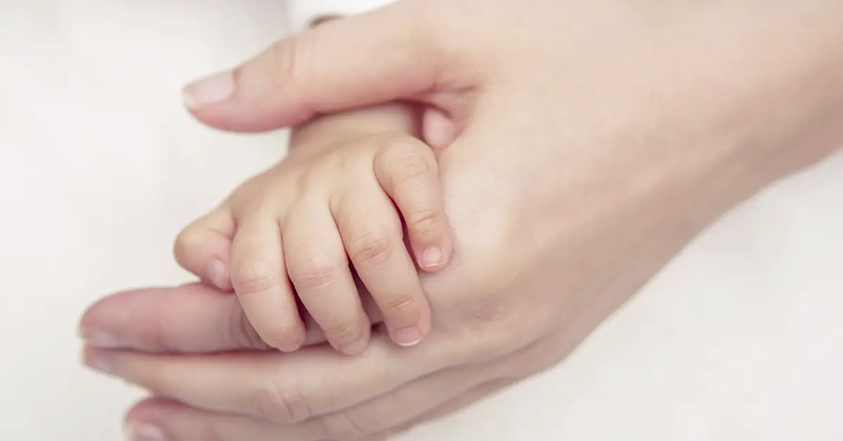 an infants hand being held by a parent's