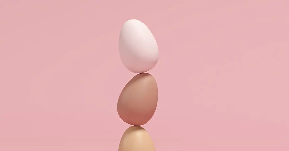 eggs balancing on each other with a pink background