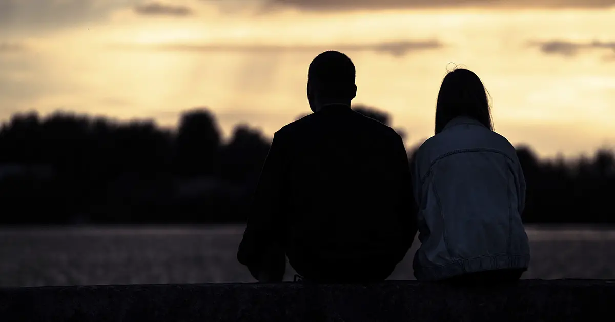 silhouette of two people watching the sunset