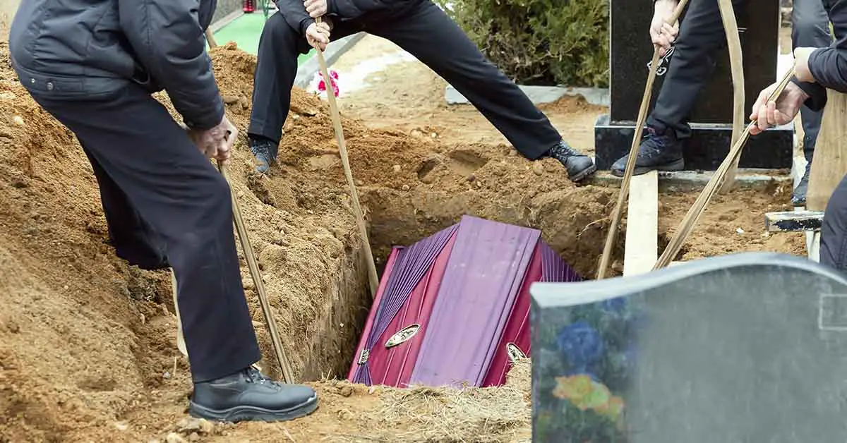 casket being placed into the ground by several people at funeral