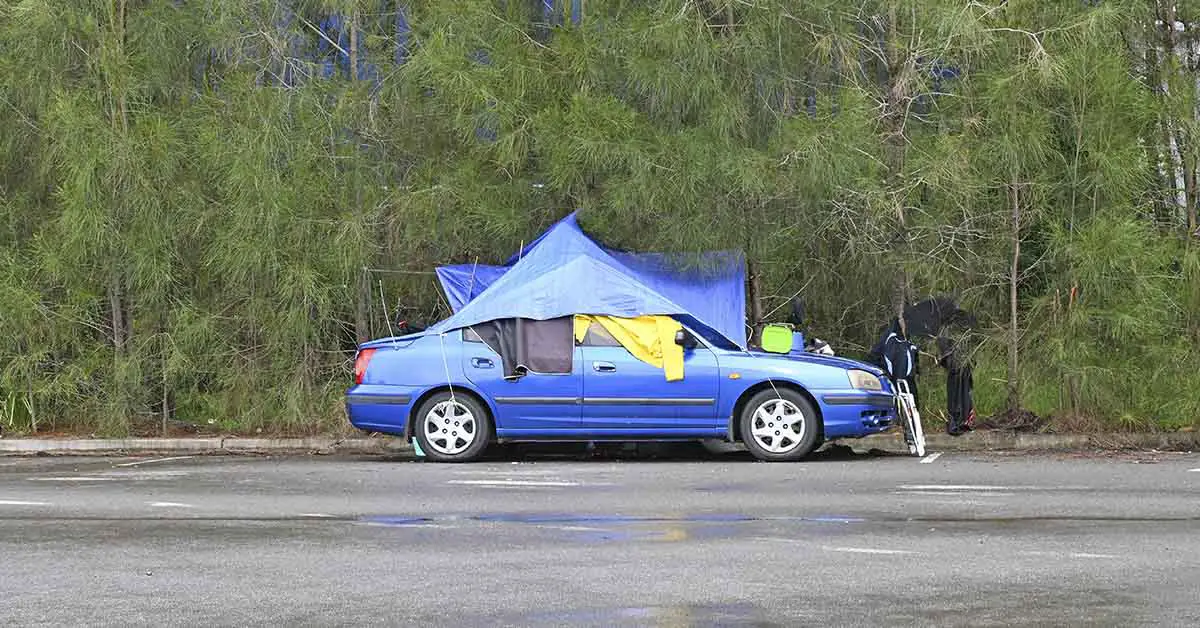 car parked on side of the road with tent set up connected to it