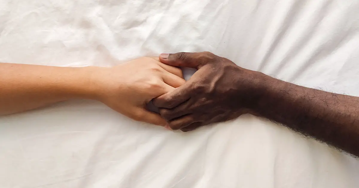 two hands holding each other, one white one black