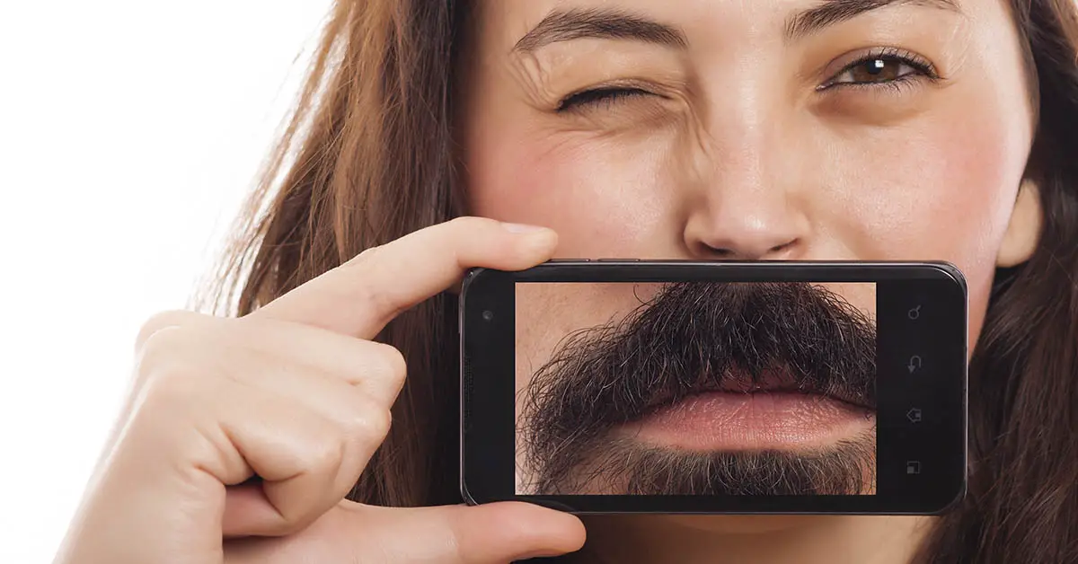 woman with smartphone placed over her face to make it appear as if she has a beard