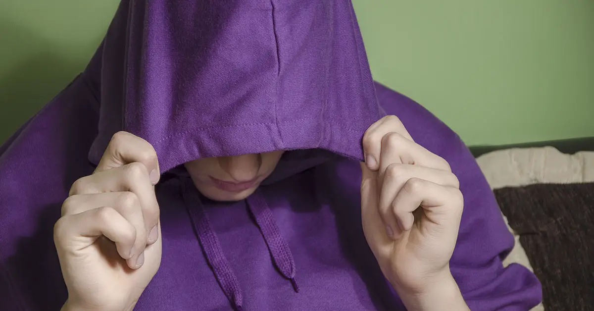teen boy wearing purple hoodie with hood placed over half of face