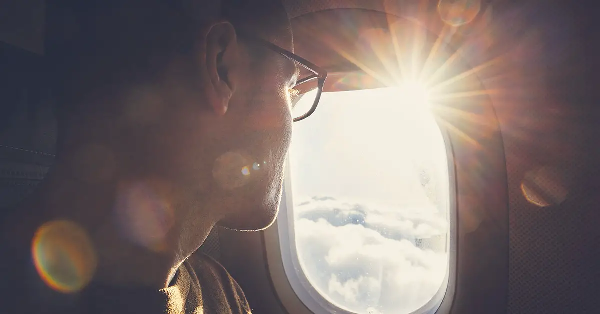 man looking out window of plane mid flight
