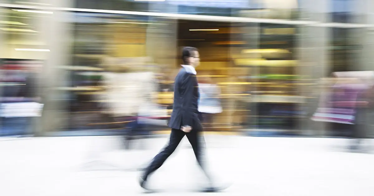 man walking briskly in urban area. Image is blurred to indicate high speed