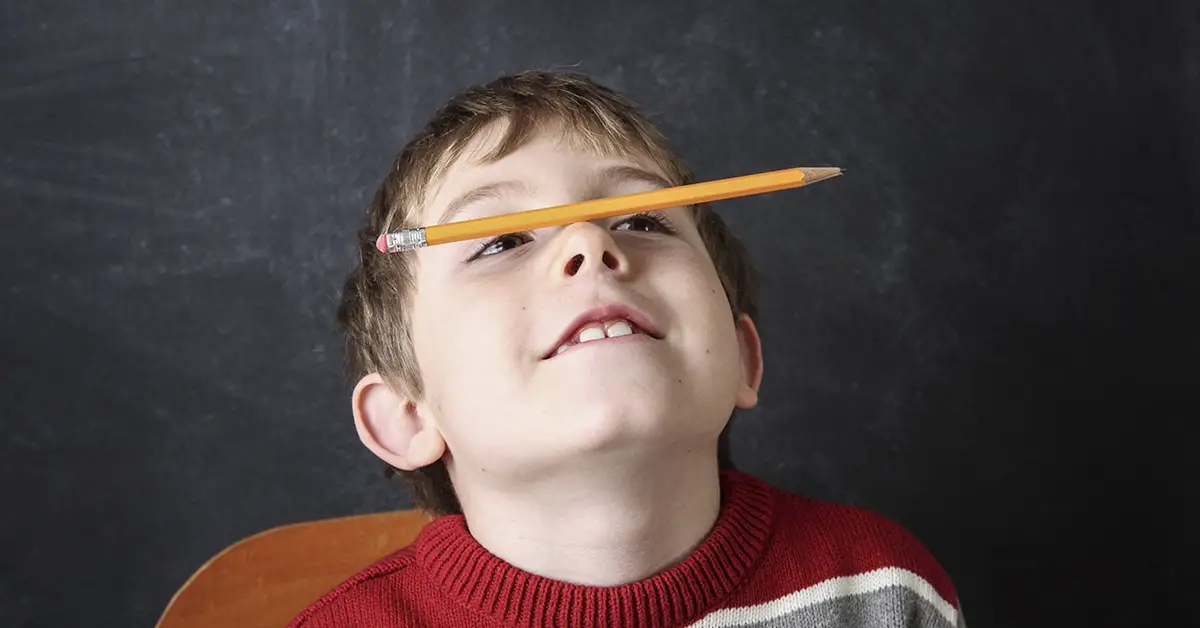 child balancing pencil on nose