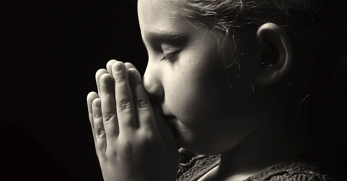black and white image, little girl praying with hands in front of face. Profile shot