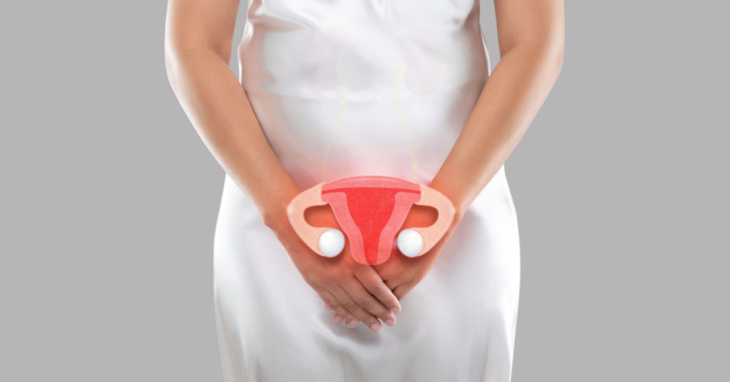 Woman in white dress with hands in front of her pelvis with a picture of uterus