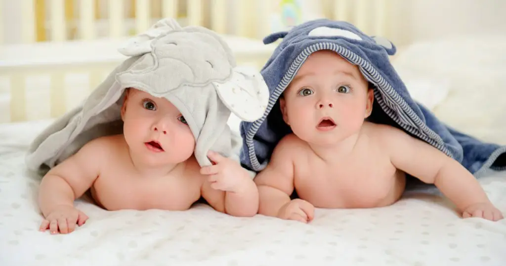  five months old baby boy twins in character towels after taking a bath or shower,