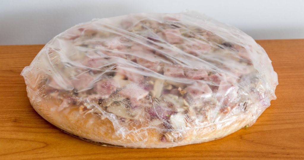 Frozen pizza in plstic with ham & mushroom.
