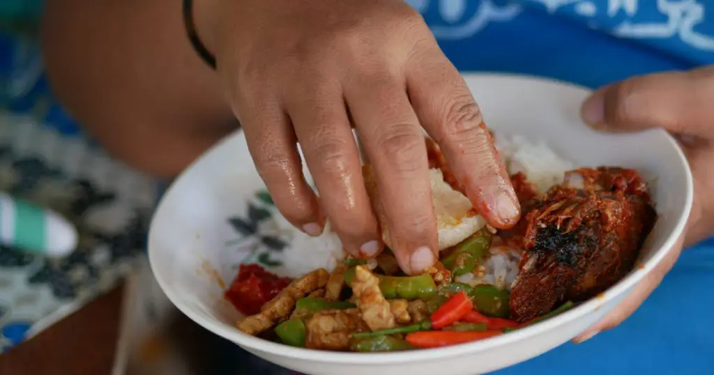An Indonesian woman eating her meals using her bare right hand, a common practice and considered a better way of eating for most Indonesian traditionally.
