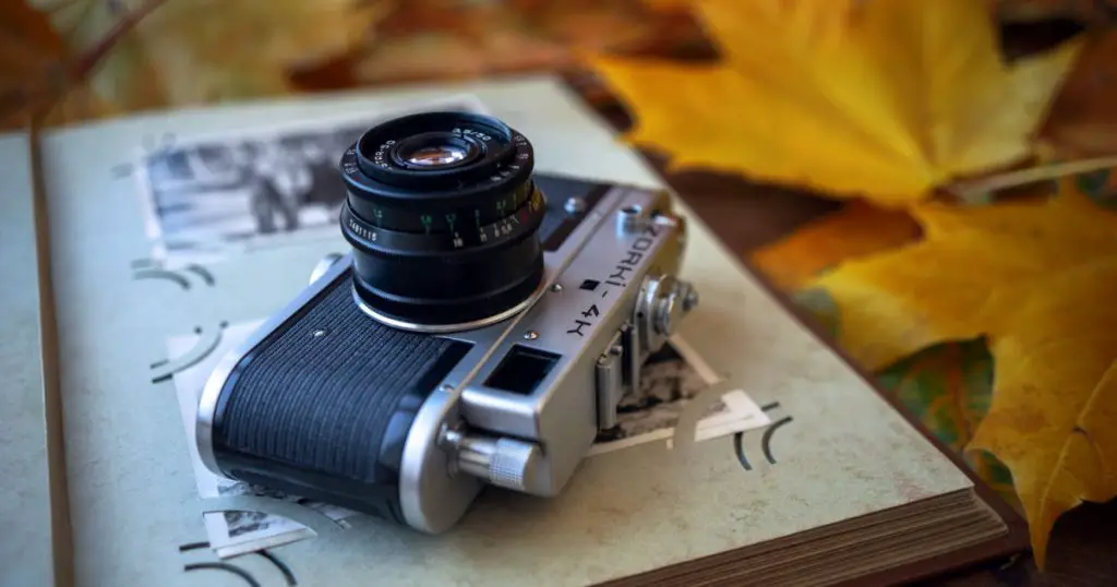 Soviet film camera Sharp-sighted 4. Old photo albums. The vintage camera is on the photo album. Autumn still life with a camera.
