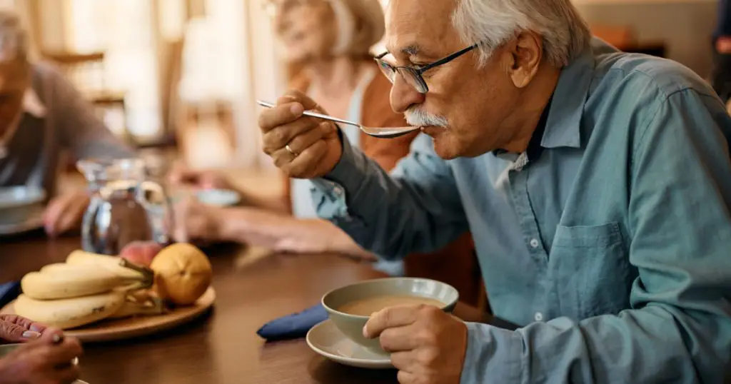 Mature man eating soup while having lunch at residential care home
