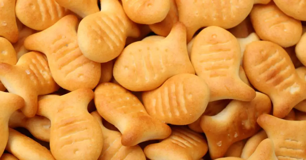 Delicious goldfish crackers as background, closeup view
