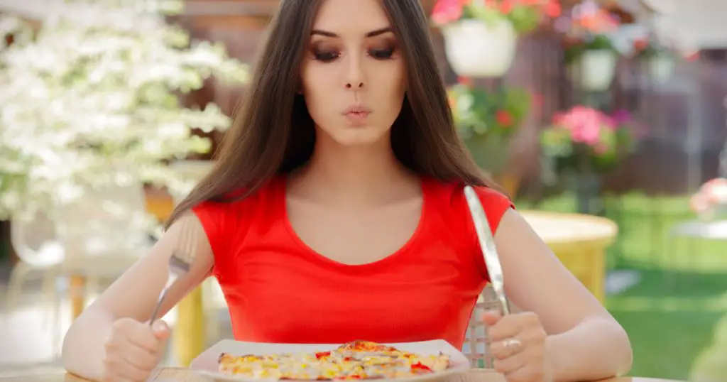 Young Woman Thinking About Eating Pizza on a Diet - Beautiful girl Making Nutrition Decisions in a Restaurant
