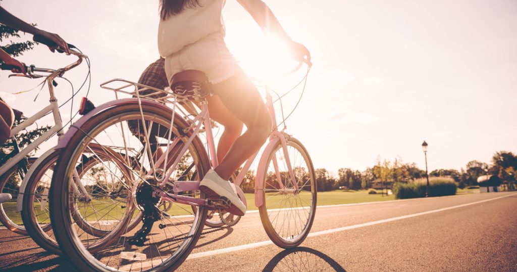 Perfect day for cycling. Low angle view of young people riding bicycles along a road together
