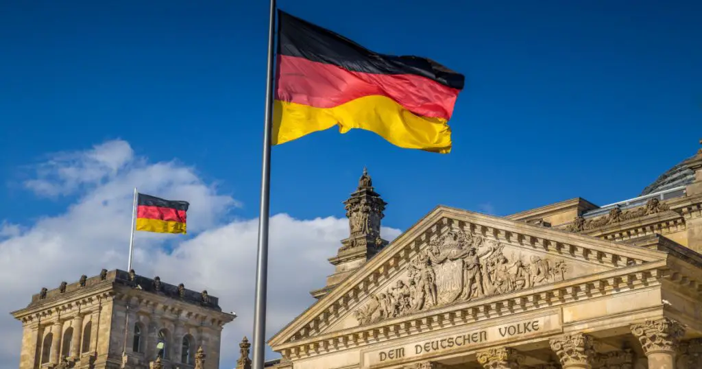 German flags waving in the wind at famous Reichstag building, seat of the German Parliament (Deutscher Bundestag), on a sunny day with blue sky and clouds, central Berlin Mitte district, Germany
