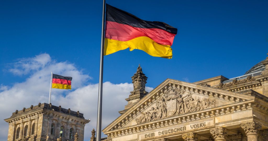 German flags waving in the wind at famous Reichstag building, seat of the German Parliament (Deutscher Bundestag), on a sunny day with blue sky and clouds, central Berlin Mitte district, Germany
