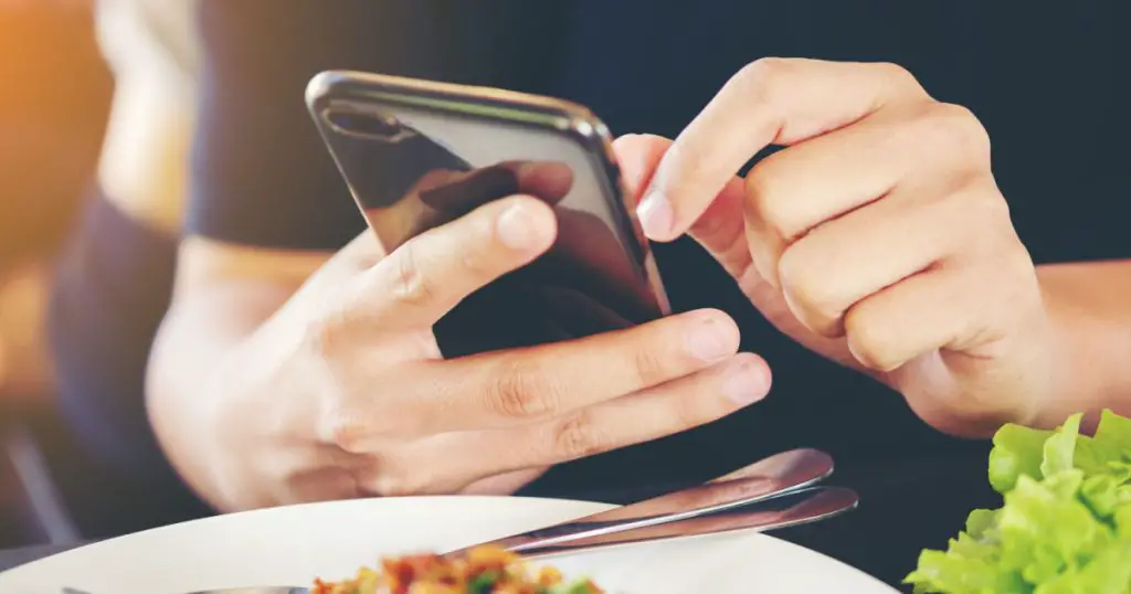 Close-up Man's hands use pointing finger Mobile smart Phone on Food table, technology and home concept
