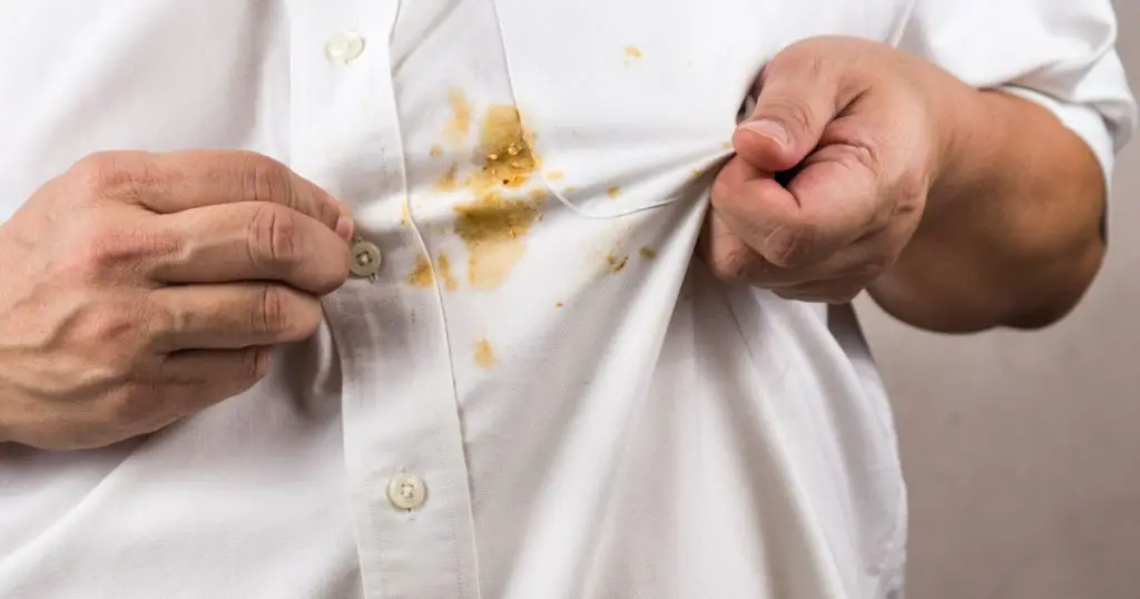 Frustrated person pointing to spilled curry stain on white shirt
